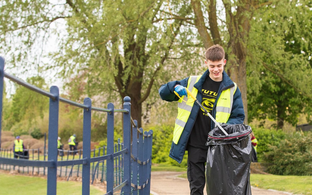 A young man litter picking in a Campbell Park